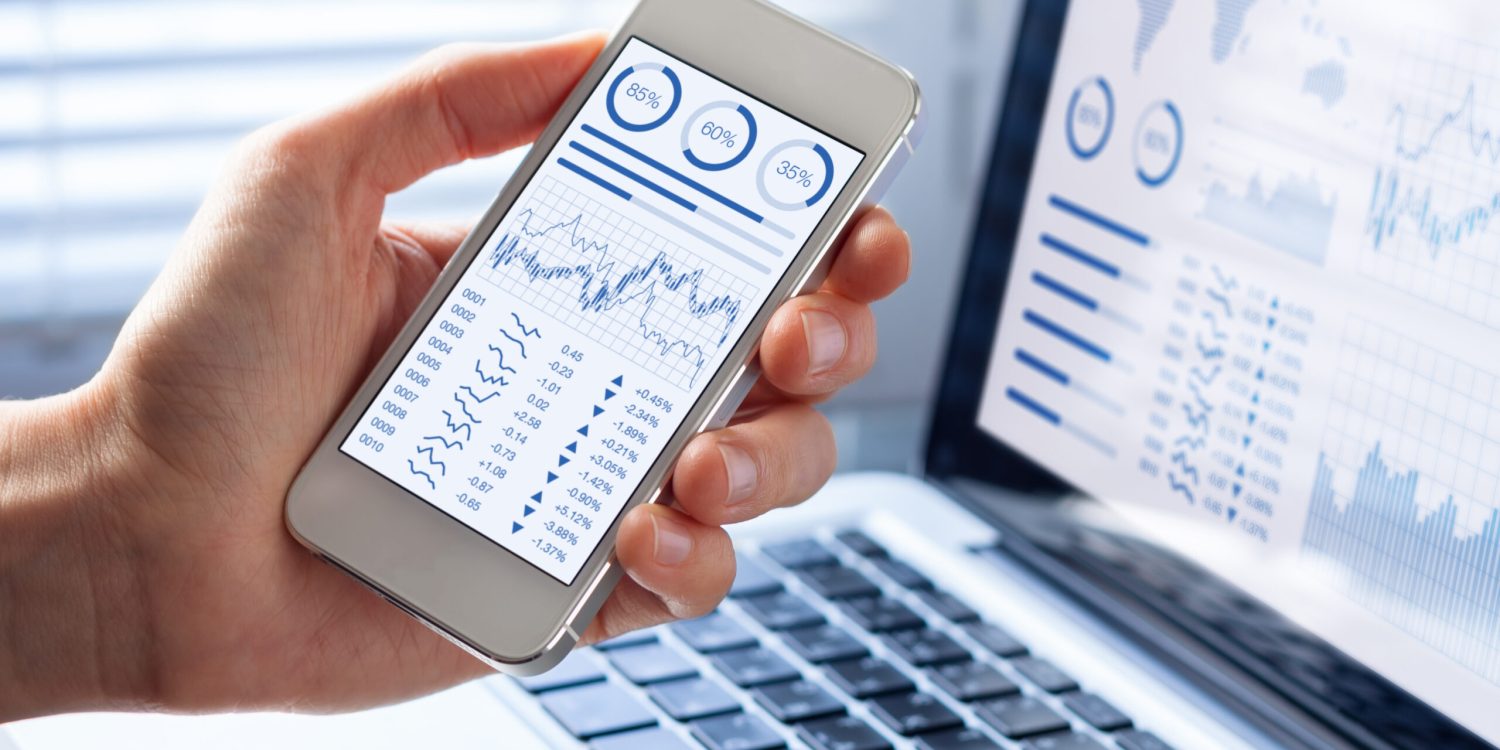 Investor analyzing stock market investments with financial dashboard, business intelligence (BI), and key performance indicators (KPI) on smartphone and computer screens
